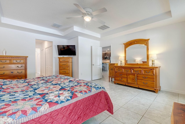 tiled bedroom with a tray ceiling, a textured ceiling, a closet, and ceiling fan