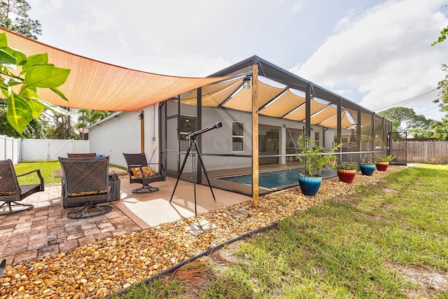 back of house featuring a lanai, a lawn, and a patio