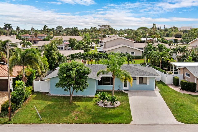 view of front facade with a residential view, concrete driveway, a front yard, and stucco siding