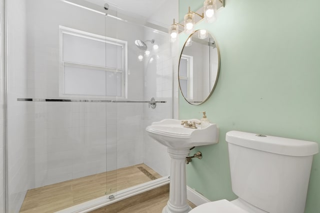 bathroom featuring toilet, wood-type flooring, and an enclosed shower