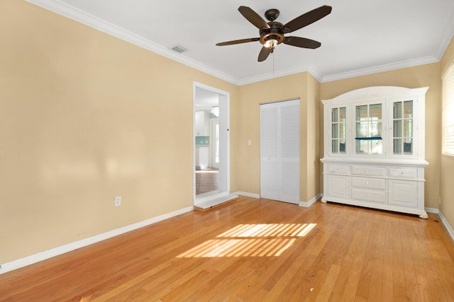 unfurnished bedroom featuring ornamental molding, a closet, light wood-type flooring, and ceiling fan