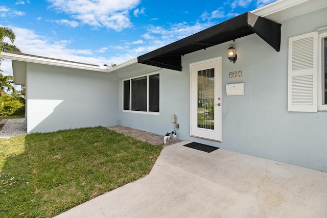 property entrance featuring a lawn and stucco siding