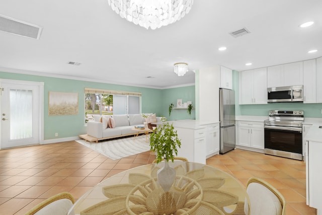 kitchen with appliances with stainless steel finishes, white cabinetry, ornamental molding, light tile patterned floors, and an inviting chandelier