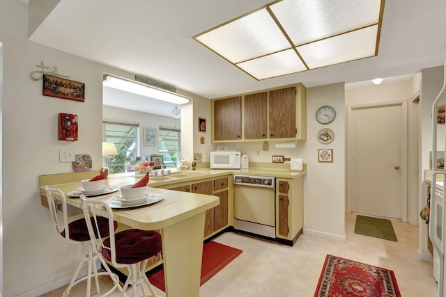 kitchen featuring a breakfast bar, kitchen peninsula, and dishwashing machine