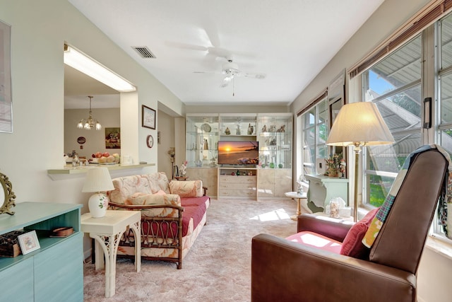 carpeted living room with ceiling fan with notable chandelier