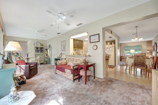 carpeted living room featuring ceiling fan with notable chandelier