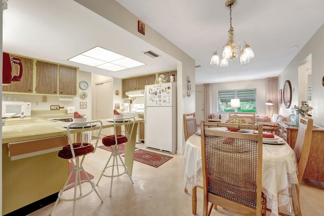 kitchen with an inviting chandelier, sink, decorative light fixtures, and white appliances