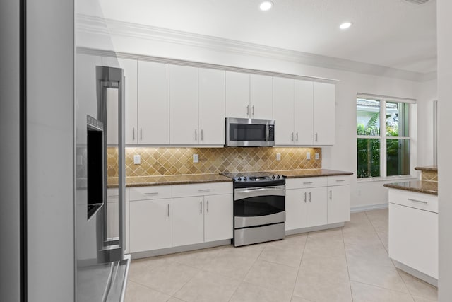 kitchen featuring stainless steel appliances, tasteful backsplash, white cabinets, dark stone counters, and light tile patterned flooring