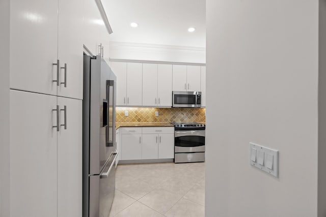 kitchen featuring backsplash, crown molding, light tile patterned floors, white cabinetry, and stainless steel appliances