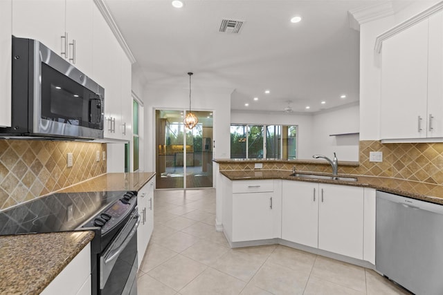 kitchen featuring sink, dark stone countertops, decorative light fixtures, white cabinetry, and stainless steel appliances