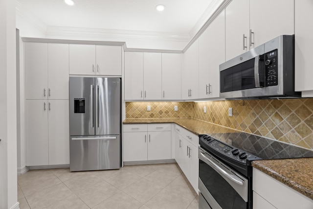 kitchen featuring dark stone counters, white cabinets, stainless steel appliances, and ornamental molding