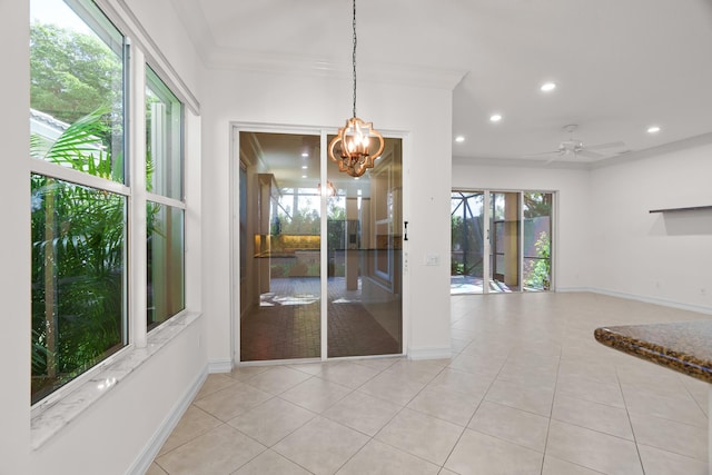 unfurnished dining area featuring ceiling fan with notable chandelier, light tile patterned flooring, crown molding, and a wealth of natural light