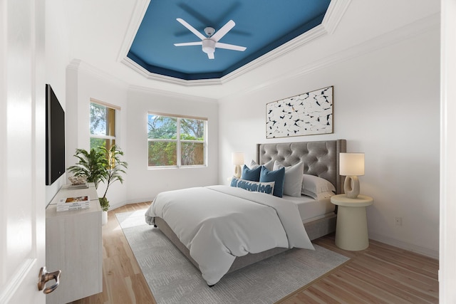 bedroom featuring ceiling fan, light hardwood / wood-style floors, a raised ceiling, and crown molding