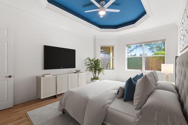 bedroom with a tray ceiling, light hardwood / wood-style flooring, ceiling fan, and ornamental molding