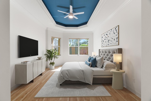 bedroom with ceiling fan, light hardwood / wood-style floors, a raised ceiling, and crown molding