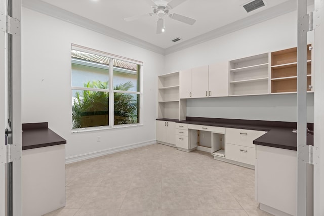 unfurnished office featuring ceiling fan, crown molding, light tile patterned flooring, and built in desk