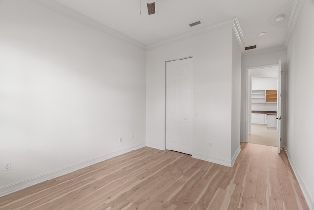 unfurnished bedroom featuring light hardwood / wood-style flooring, a closet, and crown molding