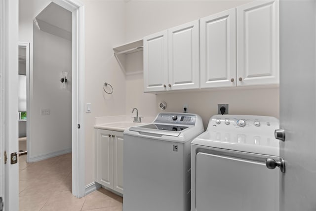 clothes washing area featuring cabinets, light tile patterned floors, washing machine and clothes dryer, and sink