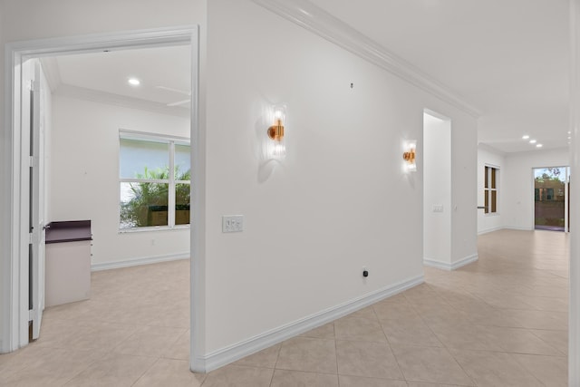 hall with light tile patterned flooring, ornamental molding, and a wealth of natural light