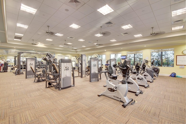 exercise room featuring a paneled ceiling, ceiling fan, and light colored carpet