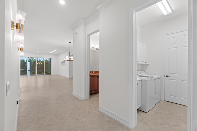 hallway with ornamental molding, light tile patterned flooring, a chandelier, and independent washer and dryer