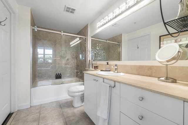 full bathroom with combined bath / shower with glass door, vanity, toilet, and tile patterned flooring