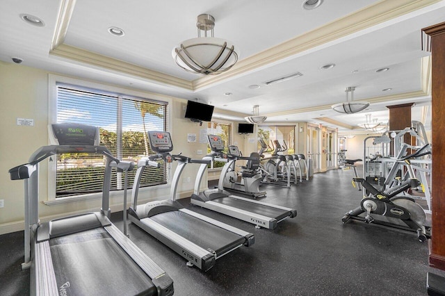 gym featuring a raised ceiling and ornamental molding