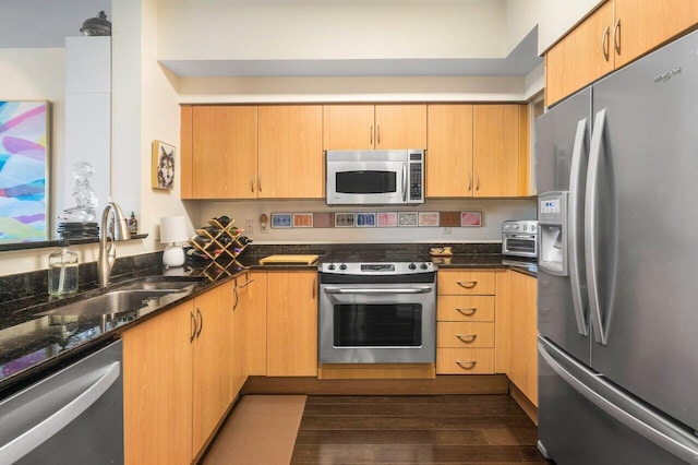 kitchen with dark stone countertops, sink, stainless steel appliances, and dark wood-type flooring