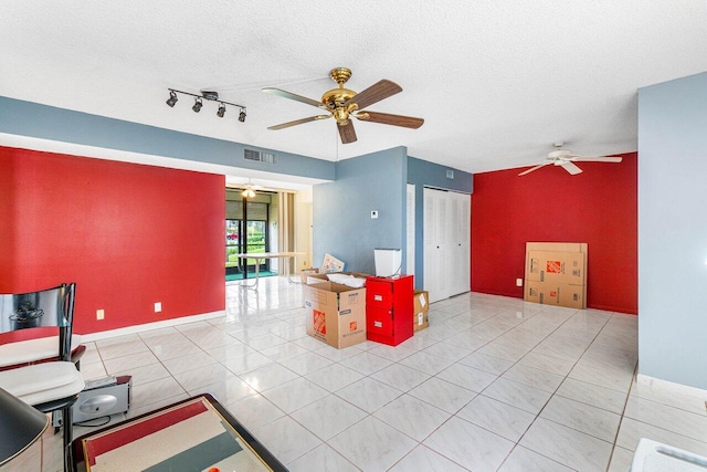 interior space with a textured ceiling, tile patterned flooring, and ceiling fan