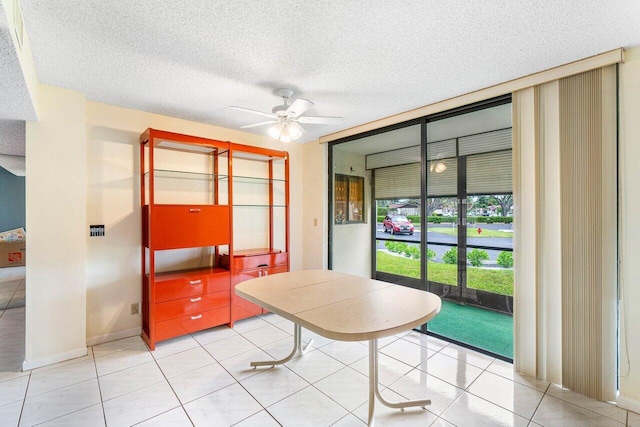 unfurnished dining area featuring ceiling fan, a textured ceiling, light tile patterned flooring, and a wall of windows