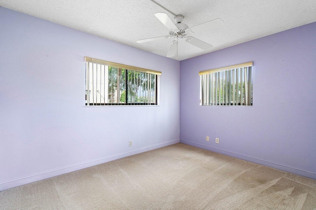 spare room featuring light carpet, a textured ceiling, ceiling fan, and a wealth of natural light