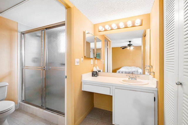 bathroom with tile patterned floors, toilet, a shower with shower door, vanity, and a textured ceiling