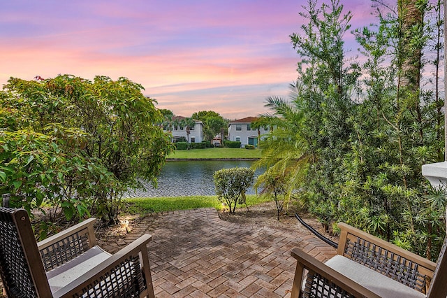 patio terrace at dusk featuring a water view