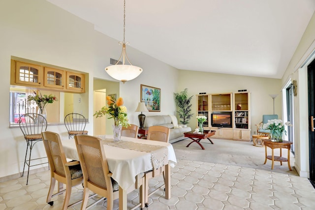 dining space with a wealth of natural light, vaulted ceiling, and a fireplace