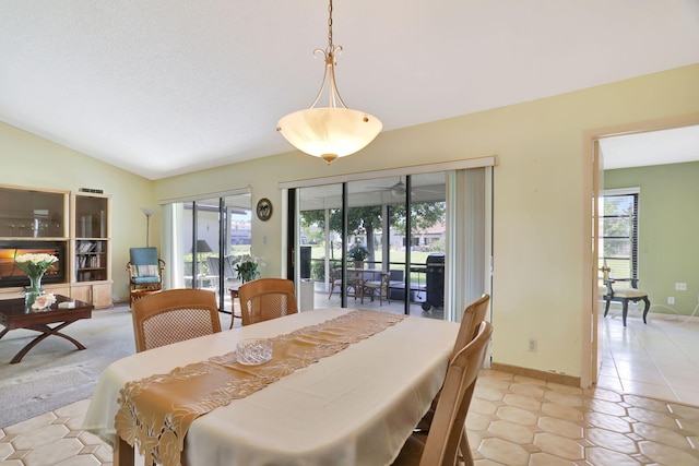 dining room featuring light tile patterned floors, vaulted ceiling, and plenty of natural light