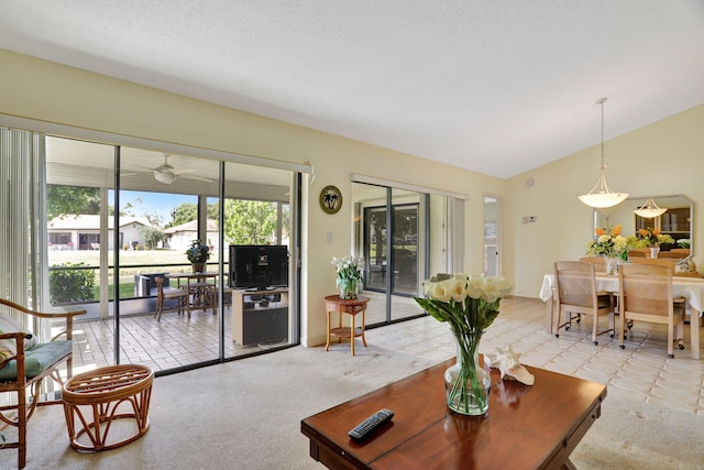 living room featuring lofted ceiling, light carpet, a textured ceiling, and ceiling fan