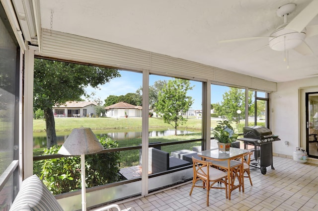 sunroom with a water view and ceiling fan