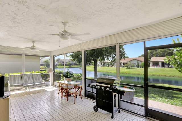 sunroom / solarium with a water view and ceiling fan