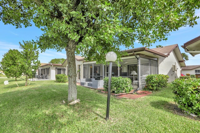 back of property featuring a lawn and a sunroom