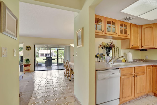 kitchen with white dishwasher, sink, vaulted ceiling, and light tile patterned floors