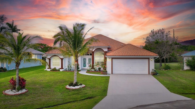 mediterranean / spanish-style house with a garage and a yard