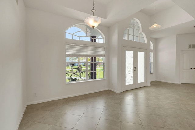 tiled entrance foyer featuring a towering ceiling and french doors