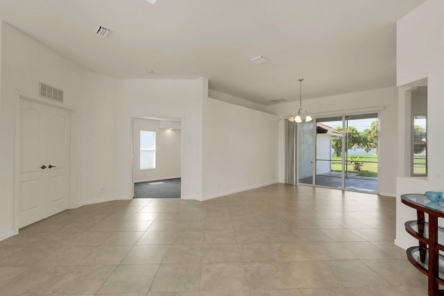 tiled empty room with an inviting chandelier