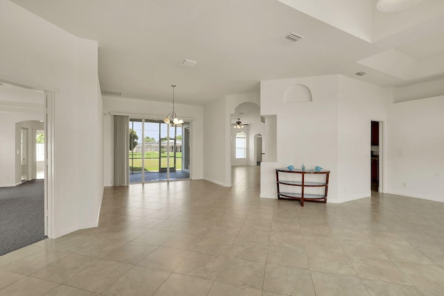 tiled spare room featuring ceiling fan with notable chandelier