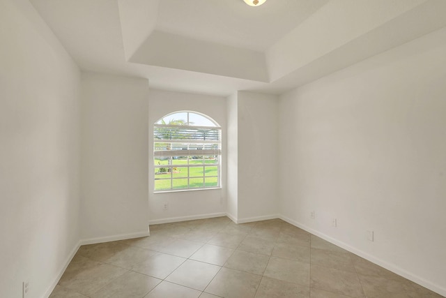 tiled spare room featuring a raised ceiling