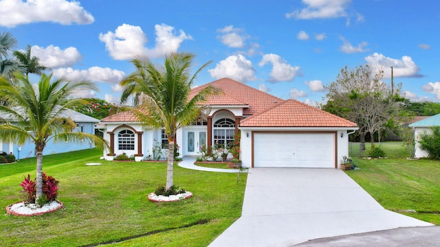 mediterranean / spanish-style home featuring a garage and a front lawn