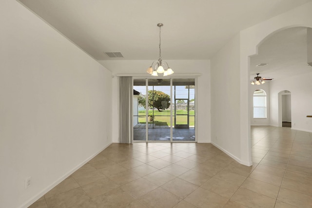 empty room with ceiling fan with notable chandelier, a healthy amount of sunlight, and light tile patterned floors