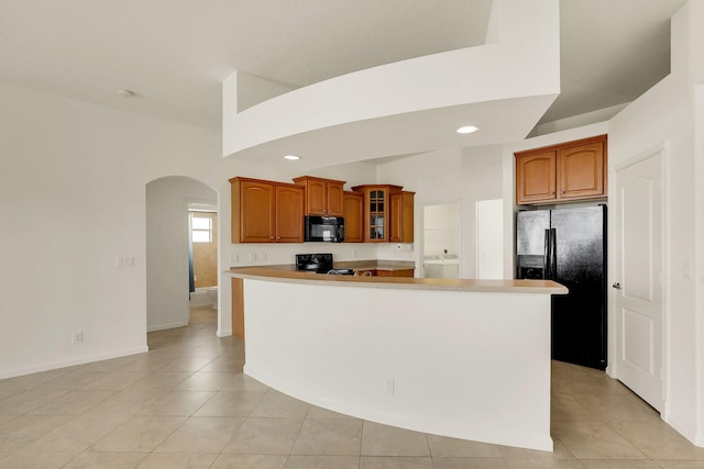 kitchen featuring black appliances, light tile patterned flooring, and a center island