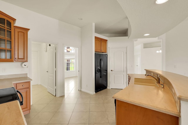 kitchen with black appliances, sink, light tile patterned flooring, and a textured ceiling