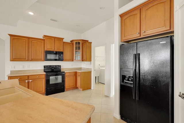 kitchen with black appliances, light tile patterned floors, and sink